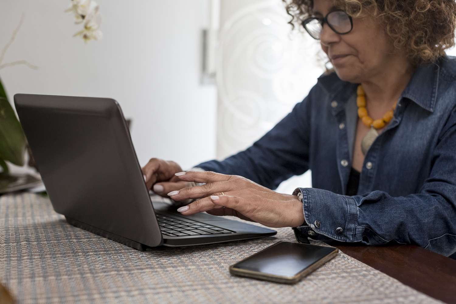 Woman typing on a laptop at her dining room table