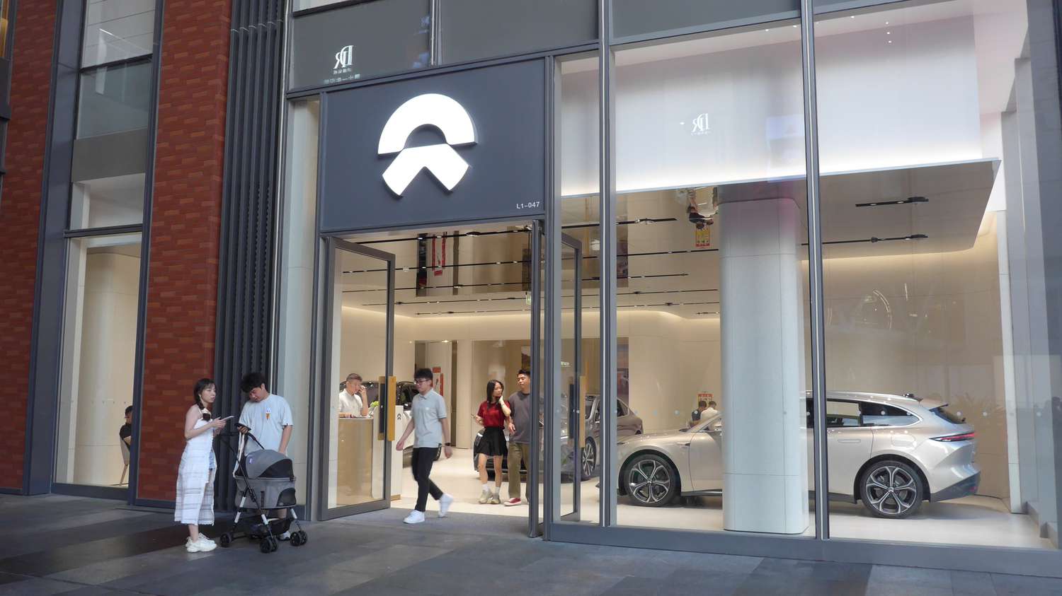 People leave a Nio store in China, with an electric vehicle seen inside the store.