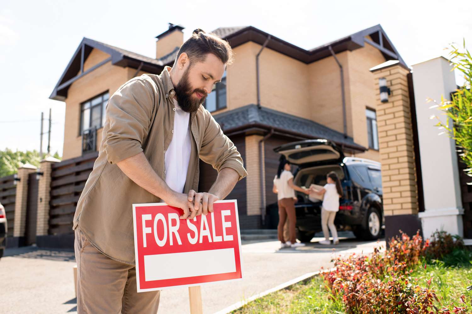 Man placing a For Sale sign outside his house