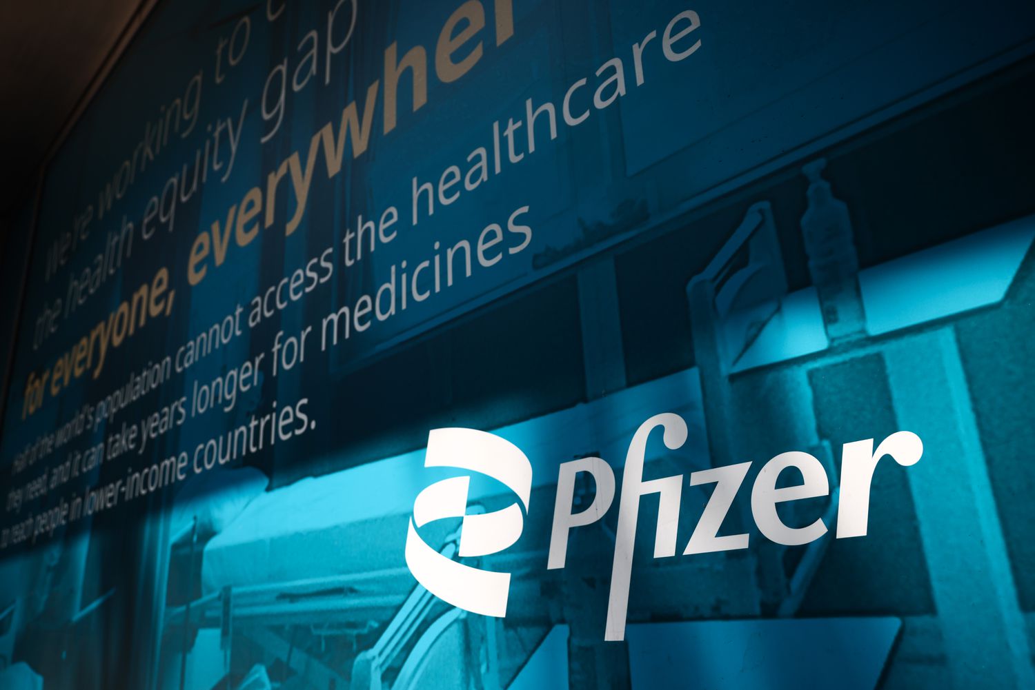 The Pfizer logo and a block of text about healthcare are seen on a blue wall.