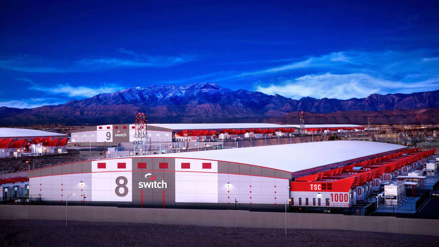 A pair of white and red Switch data centers are seen in front of mountains and a blue sky.