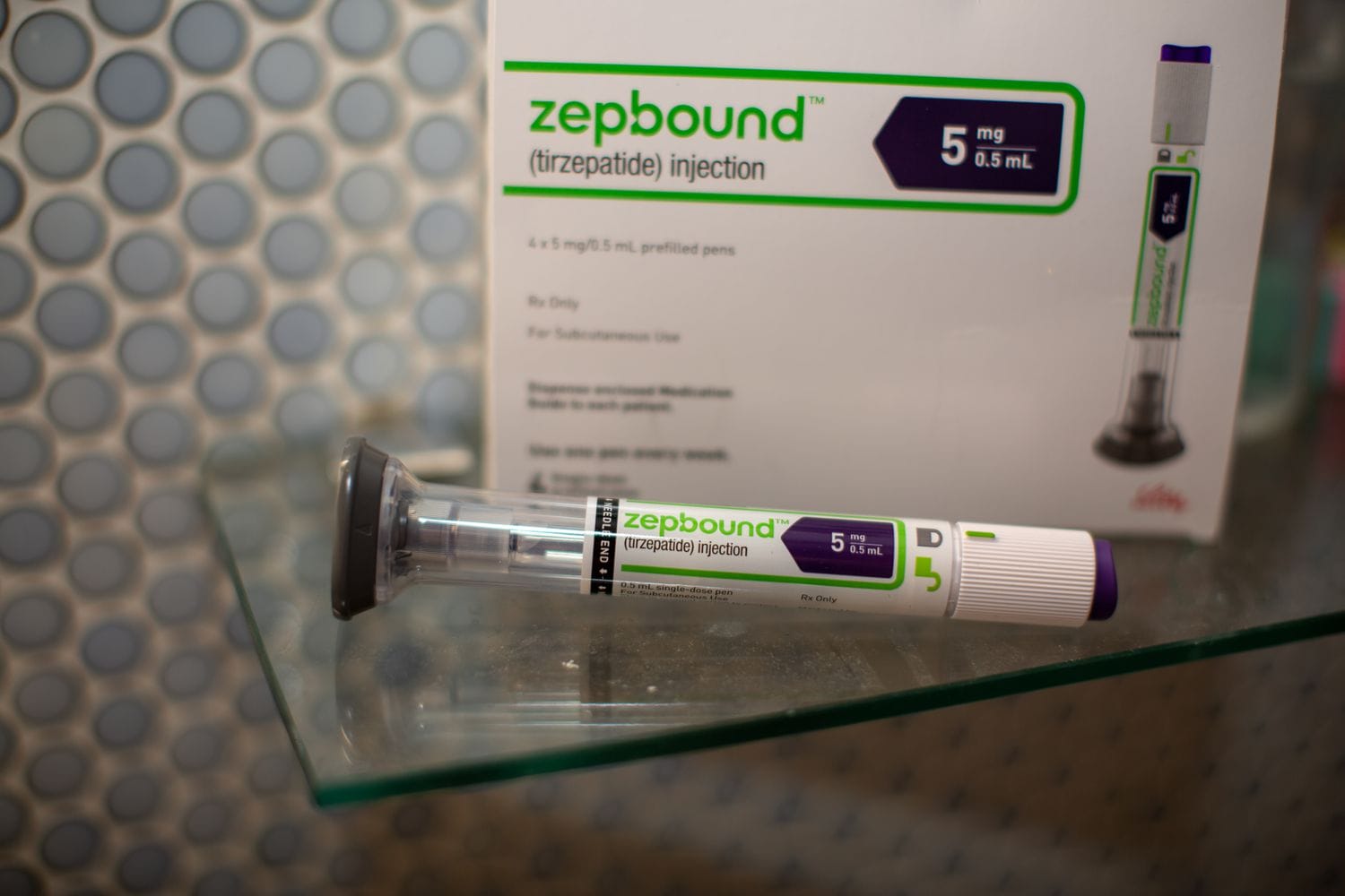 A white, green, and purple Zepbound injection pen on a table in front of a box for the medication