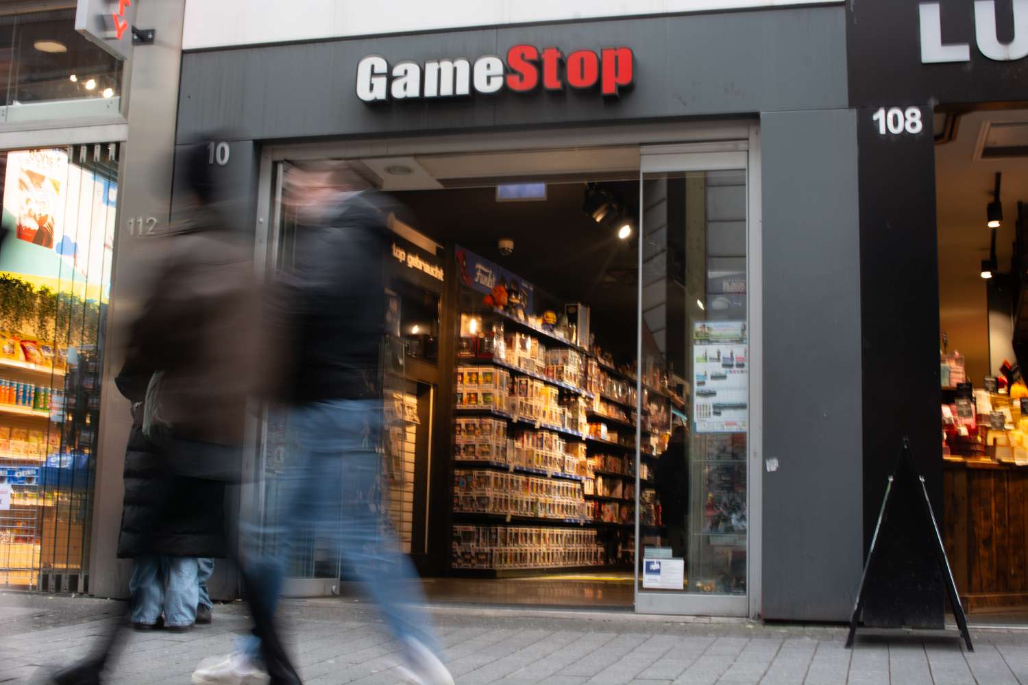 Pedestrians pass a GameStop retailer store front. 