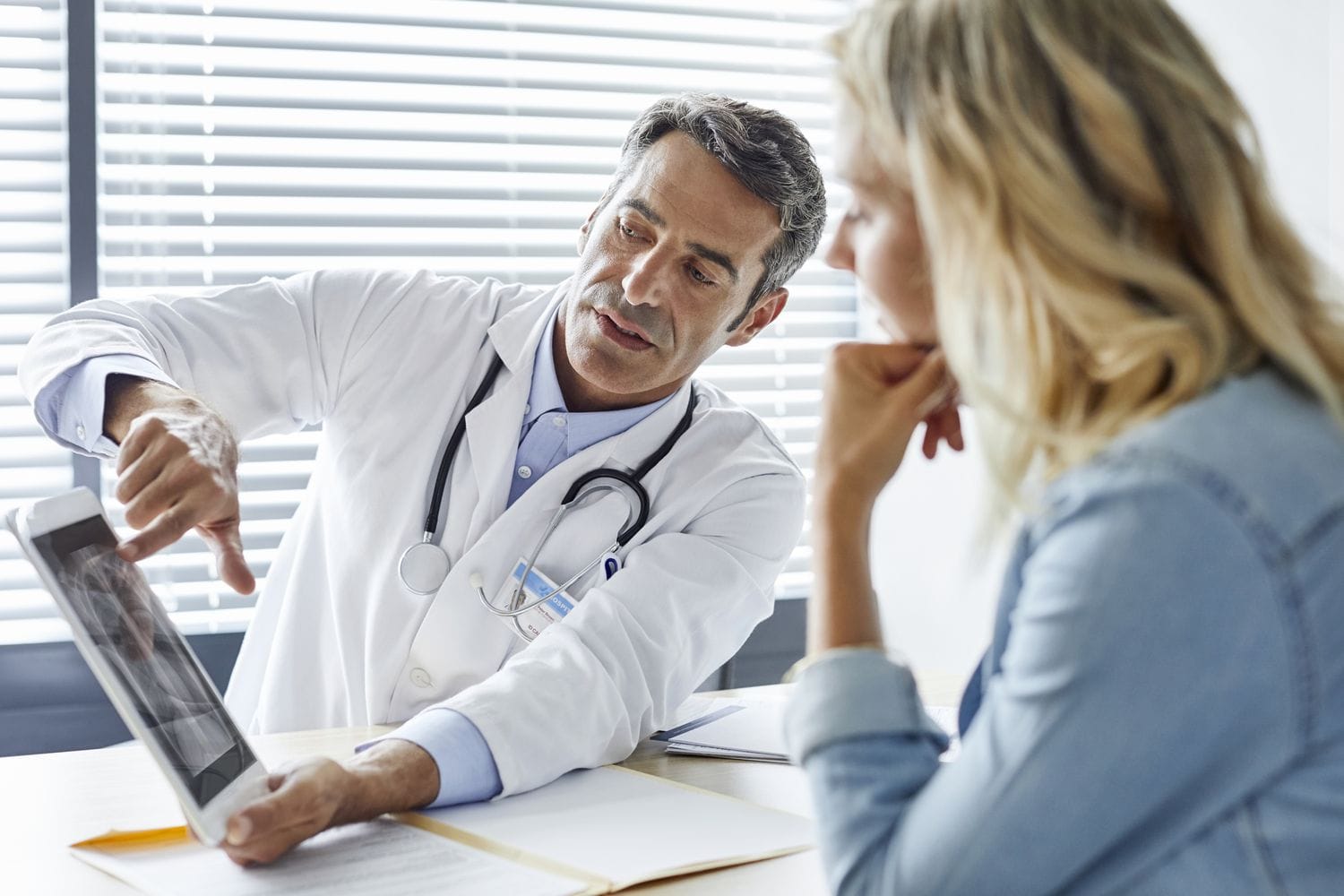 Doctor shows digital tablet with X-ray to woman