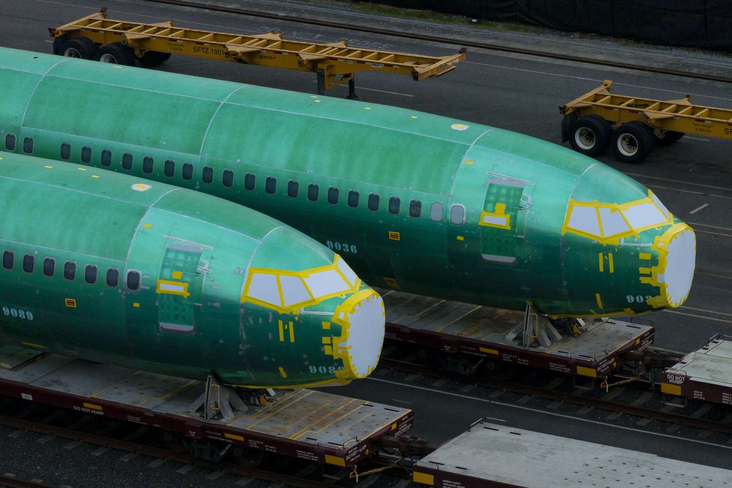 A pair of green, in-progress Boeing 737 Max fuselages are seen on train tracks.