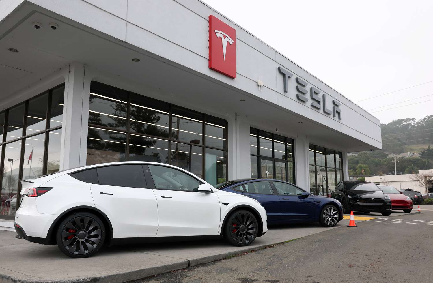 Four Tesla vehicles are seen outside the building of a Tesla dealership.