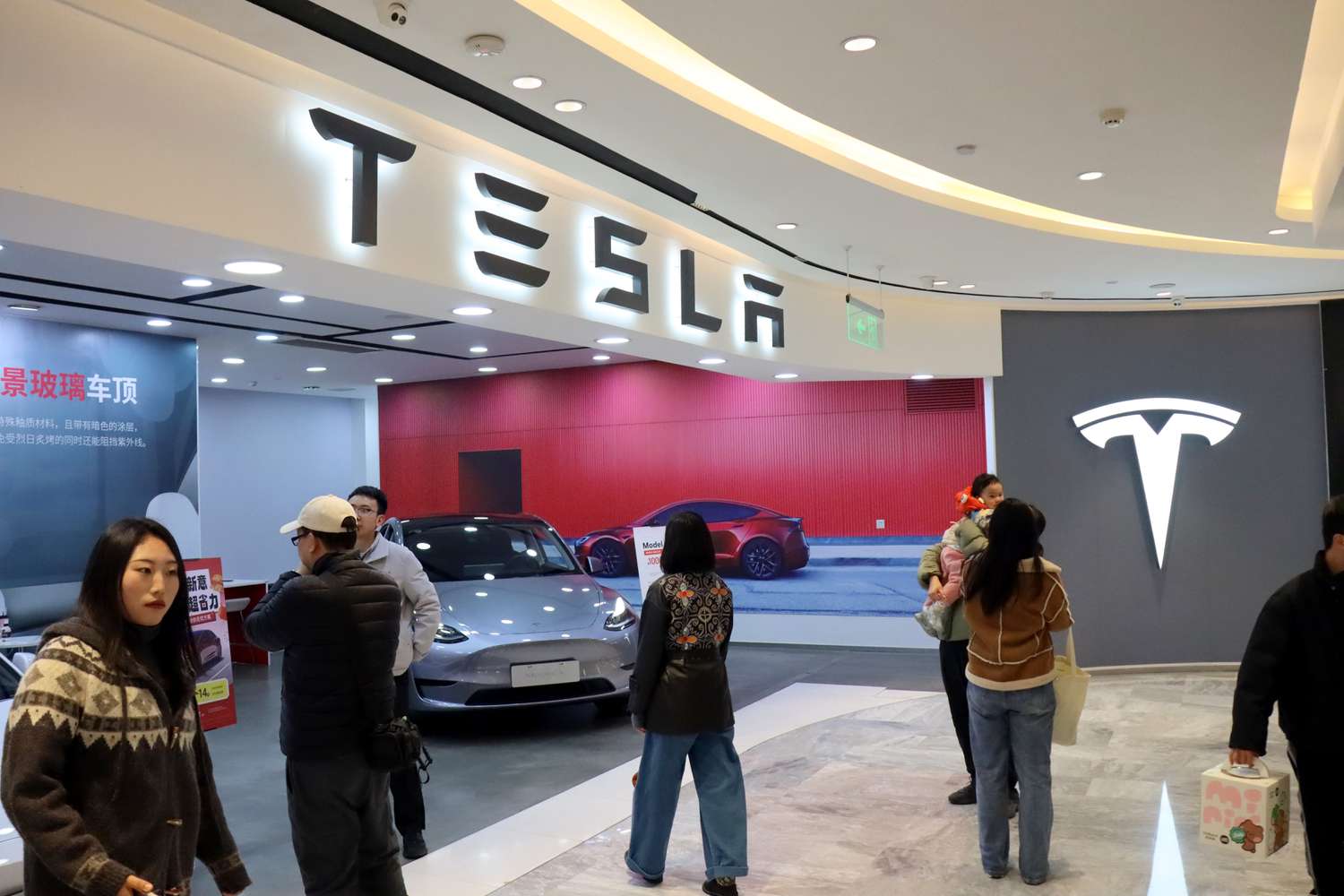 People shop for a Tesla car in Yichang, China, on Dec. 31, 2024