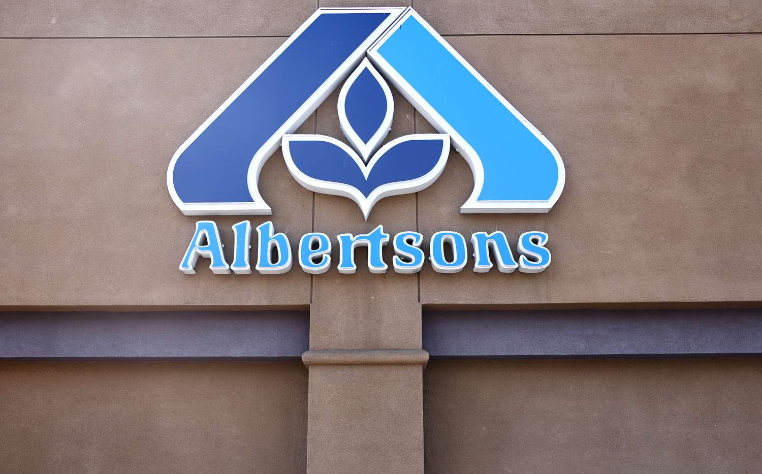 The blue Albertsons sign is seen on the side of a store