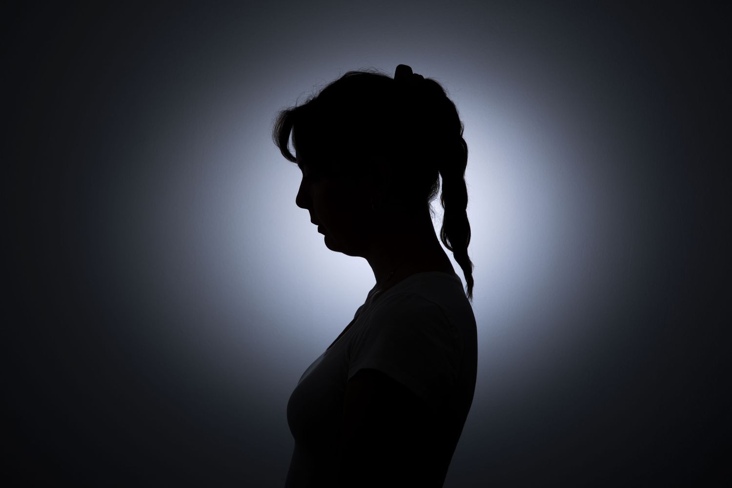 Silhouette of a woman stands out against a white wall